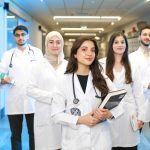 Grupo diverso de estudantes de medicina usando jalecos em um corredor universitário