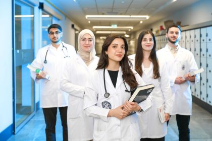 Grupo diverso de estudantes de medicina usando jalecos em um corredor universitário
